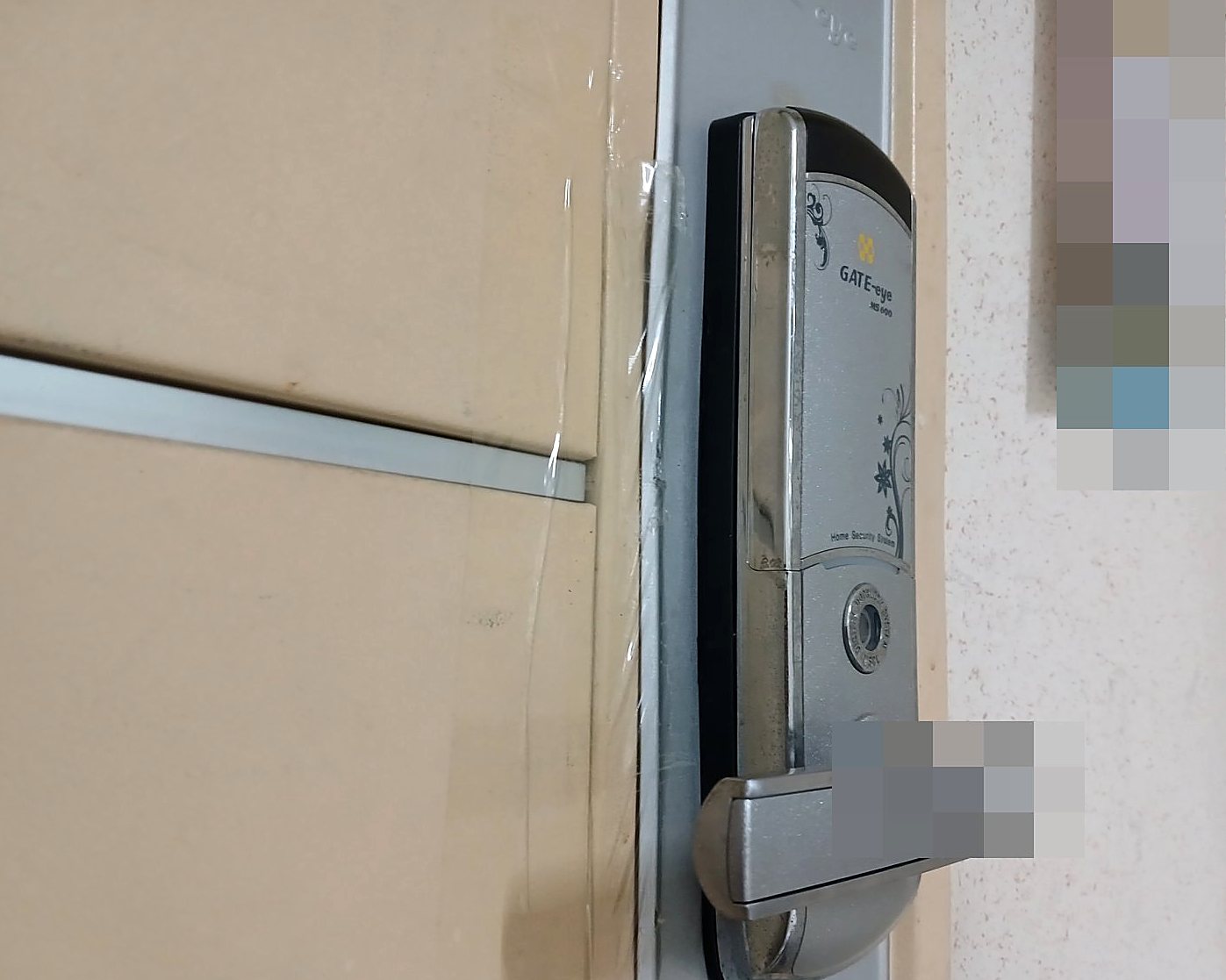 오정구 고강1동 출장 — 베이지색 문 가장자리 은색 판에 달린 은색 레버형 도어락, 꽃 덩굴 무늬와 아래쪽 둥근 구멍