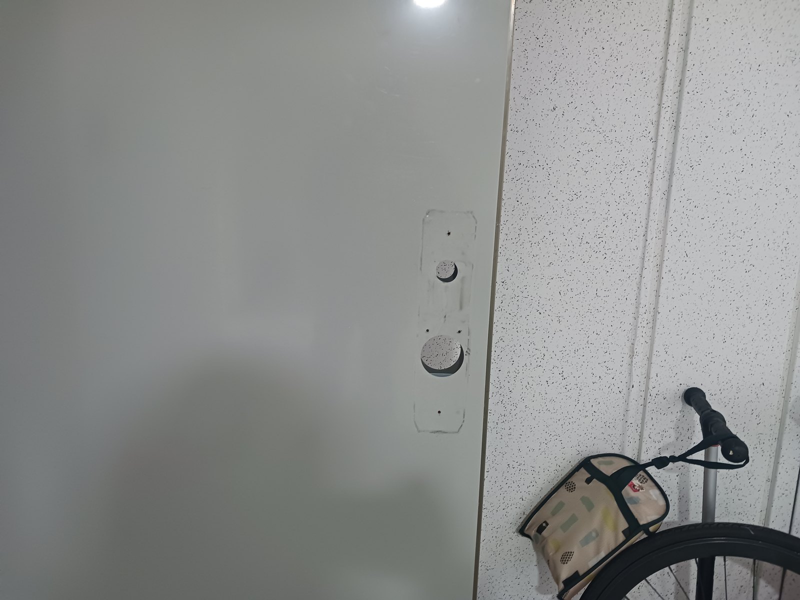 오정구 원종2동 출장 — 도어락을 떼어 낸 회녹색 문의 받침 자국과 둥근 구멍 두 개, 옆 벽 앞의 자전거